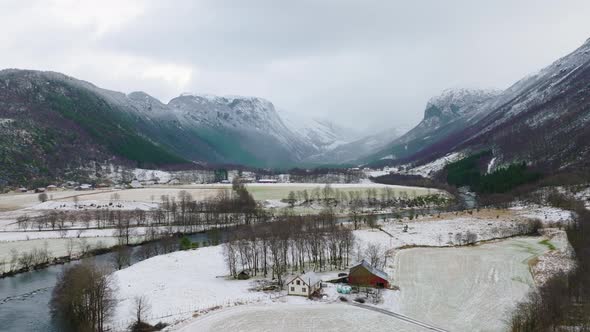 Scenic flight up secluded valley with river and misty mountains; snowy terrain