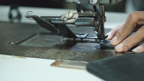 Close-Up Of Tailor Working On Sewing Machine in leather factory background