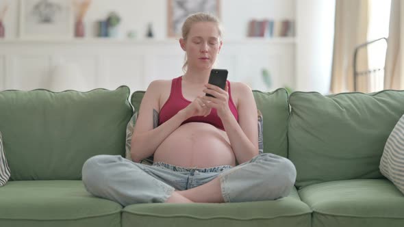 Pregnant Woman Browsing Internet on Smartphone at Home