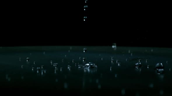 Slow motion of water droplets falling on black background