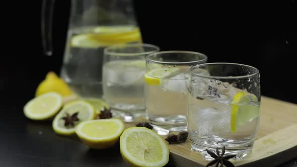 Add Ice Cubes To Lemon Juice in Glass with Lemon Slices. Alcoholic Cocktail