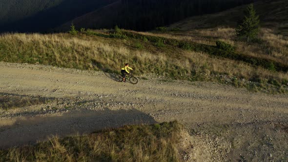 Aerial Mountain Road Cycling View Man Biking Among Spring Grass Sunny Day