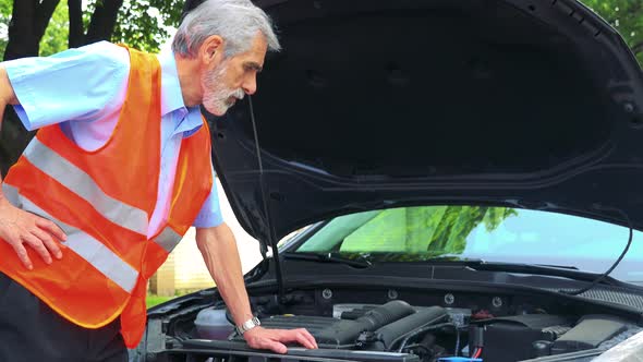 Senior Man Wears Warning Vest, Controls Engine of the Car and He Doesn't Know What To Do