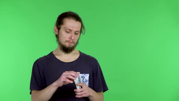 A Caucasian Man Holds a Bundle of Money in His Hands and Scatters It