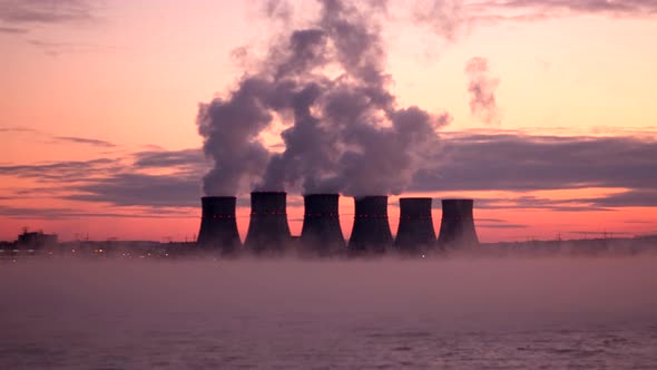 Smoke Escapes From the Steam Pipes of a Nuclear Power Plant Against a Dramatic Red Sky
