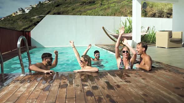 Happy friends enjoying summer day in swimming pool