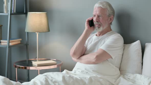 Old Man Talking on Smartphone in Bed 