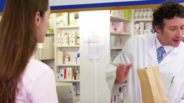 Pharmacist giving medicine package to customer