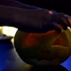 A Man Lights a Candle in an Orange Halloween Pumpkin on a Dark Background with a Bokeh Photo - VideoHive Item for Sale
