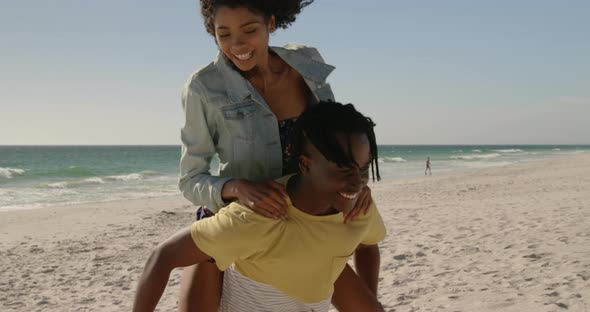 Man giving piggyback ride to woman on the beach 4k