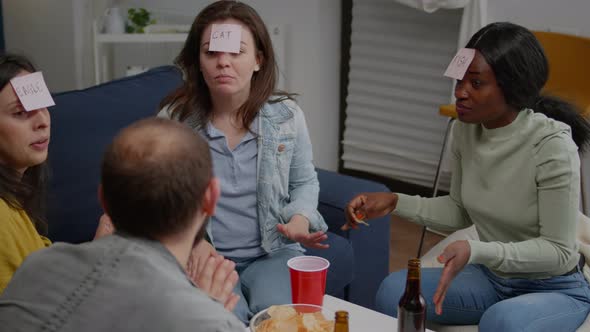 Mixed Race Friends Gathering in Living Room Playing Guess Who Game