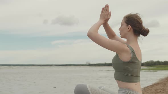 Young Woman Practicing Yoga by Water