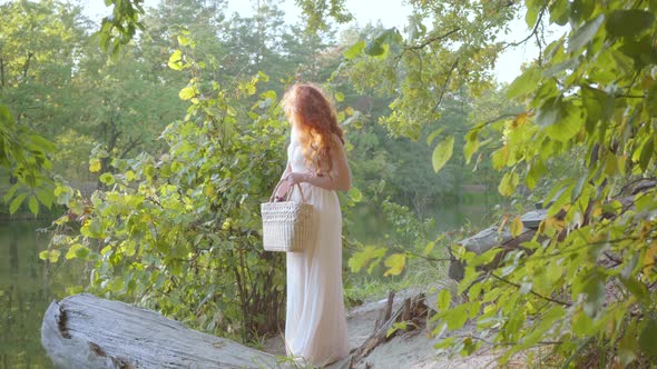 Young Elegant Caucasian Girl Dressed in Light Long White Clothes Stands in the Autumn Forest on the