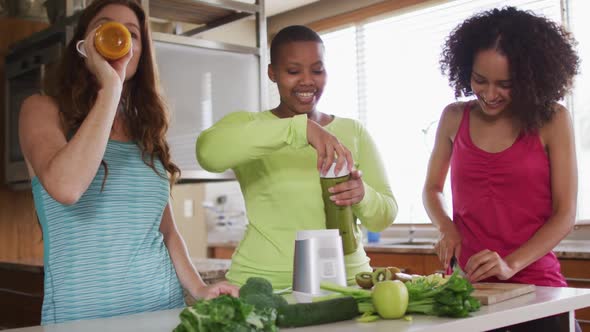 Diverse happy female friends trying healthy drinks at home