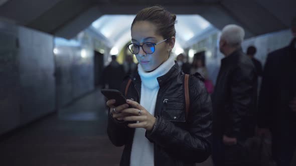 Woman Standing in the Entrance of a Subway Station Using a Smartphone