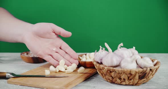 Male Hand Puts the Peeled Garlic Cloves on a Cutting Board. 