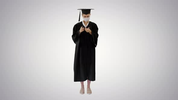 Graduation Student in Medical Mask Using Sanitizer on Gradient Background