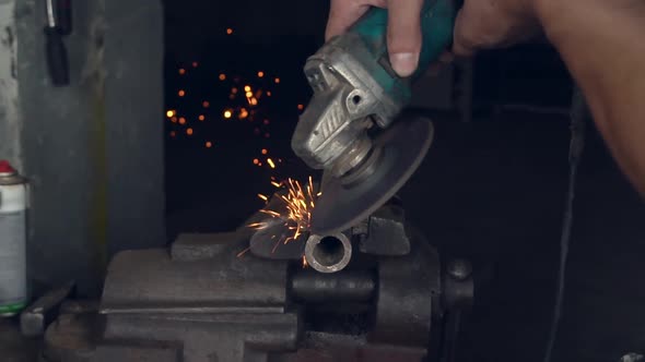 man works with a circular saw. Sparks fly from the hot metal.