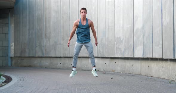 Front View of Young Athletic Man Doing Squats Exercises with Jumps Sports Training Alone