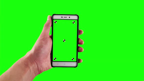 Man Holds Old Fashioned Smartphone with Tracking Markers on Display Against Green Screen Background