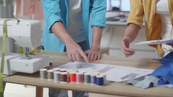 Close Up Of Male And Female Designers' Hands With Sewing Machine Rearranging Clothes Drawing Picture