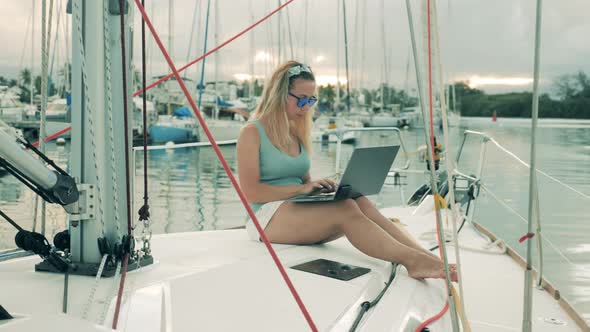 Working Woman Types on a Laptop While Sitting at a Yacht.