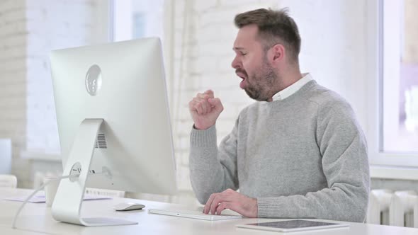 Sick Man Coughing While Working on Desktop