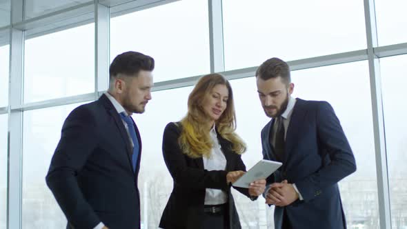 Businesspeople Looking at Tablet and Talking