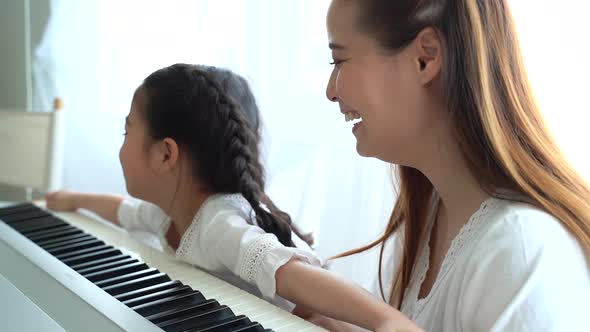 Asian Mother Teaching Daughter to Play Keyboard