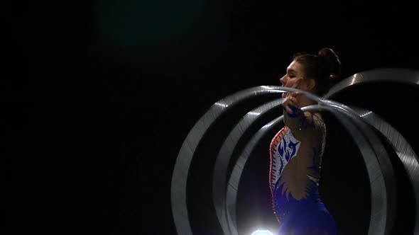 Gymnast Turns on Her Hands a Lot of Hoops. Black Background. Slow Motion