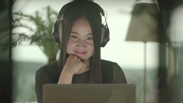 Young Asian Female Listening Music on Laptop Computer at Home