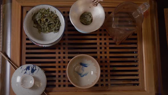 Master Pouring Hot Water From Teapot in Gaiwan with Green Tea on Tea Table