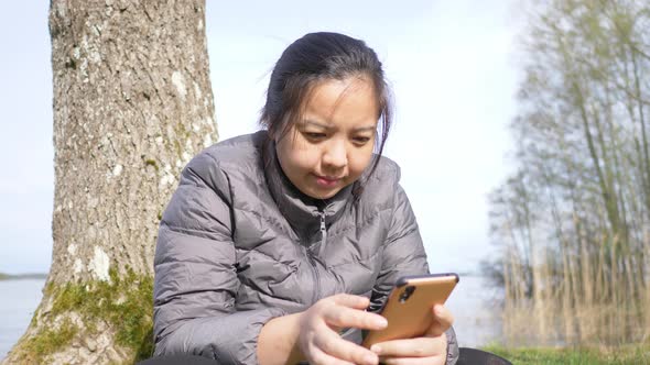 Asian woman sitting and using smartphone to look a photo taken