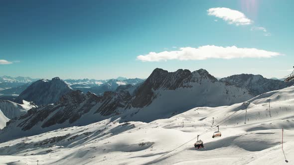 Drone shot of ski lifts while people participating in winter sports in the background - Zugspitze, B