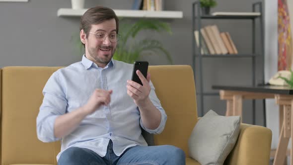 Young Man Having Success on Smartphone at Home