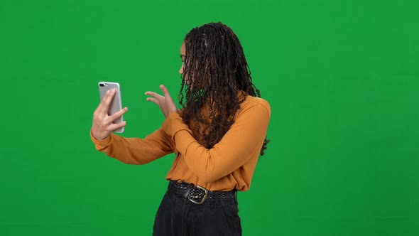 Positive Cute Teen Girl Talking at Smartphone Video Chat Pointing Around on Green Screen