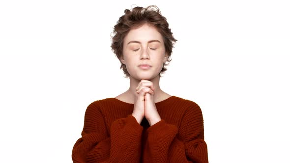 Portrait of Brunette Woman Keeping Hands in Praying Wishing Luck with Closed Eyes Over White