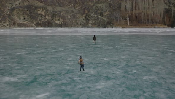 Aerial View Over Silhouette Of People Ice Skating On Frozen Khalti Lake At Ghizer Valley. Circle Dol