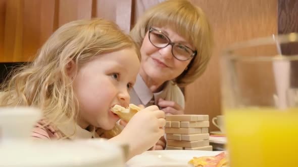 Cute Girl Eating Pizza at Cafe with Grandma