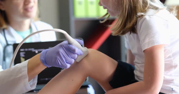 Doctor Conducts Ultrasound Examination of Child Knee Joint in Clinic Closeup