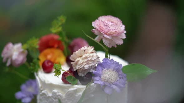 Beautiful cherry toppings and wildflower arrangement on top of a detailed white wedding cake