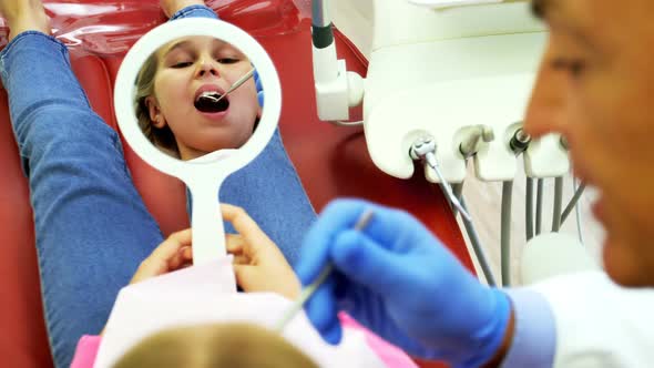 Dentist examining a young patient with tools