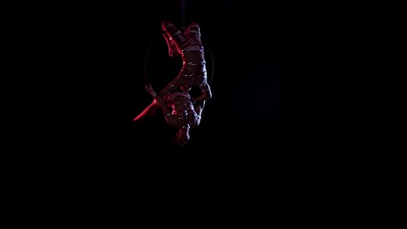 Two Girls Are Circling in a Hoop for Aerial Acrobatics. Black Background. Slow Motion