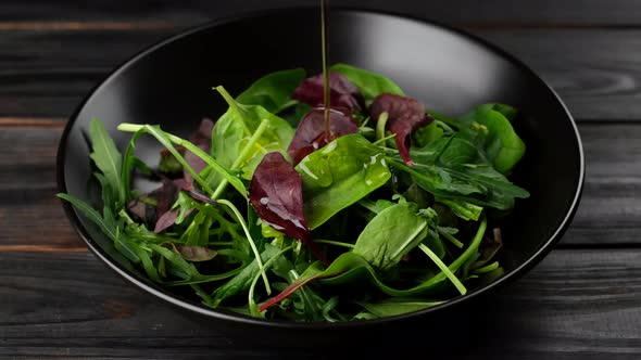 pour olive oil on fresh green salad with arugula, spinach. healthy lifestyle concept 