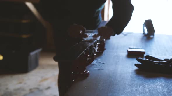 Slow-motion shot of person waxing skis, scraping wax off of ski.