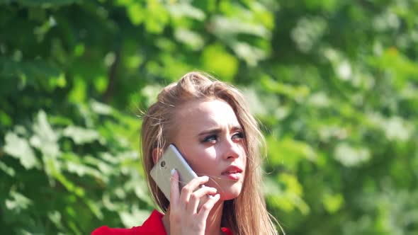 Sad woman's face outdoors. Beautiful young female talking on the mobile phone.