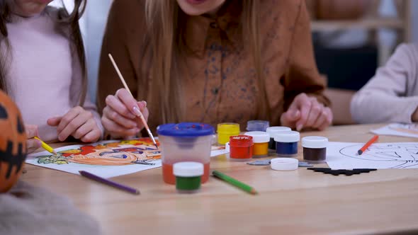 The Family is Preparing for Halloween and Drawing Pumpkins on Paper with Gouache Sitting at the