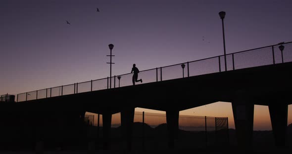 Silhouette of man running on bridge in the evening