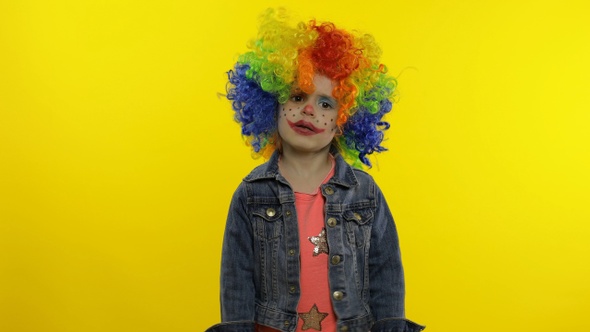 Little Child Girl Clown in Rainbow Wig Making Silly Faces, Fool Around, Smiling, Dancing. Halloween