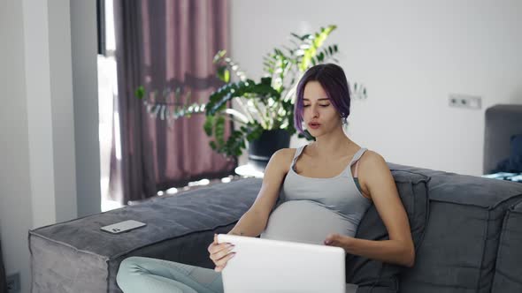 Young Pregnant Woman Attending Virtual Session with Doctor on Laptop